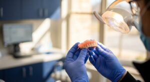 Dentist examining a denture under task light during repair evaluation at View Dental Raleigh